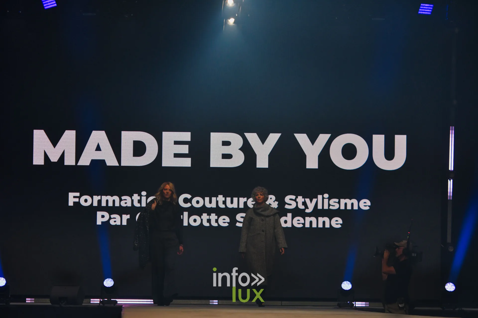 Deux participantes entrent sur le podium devant l’écran « Made by You » — Made by You, école de couture et de stylisme de Charlotte Spoidenne, Lux Fashion Week 2026, Arlon
