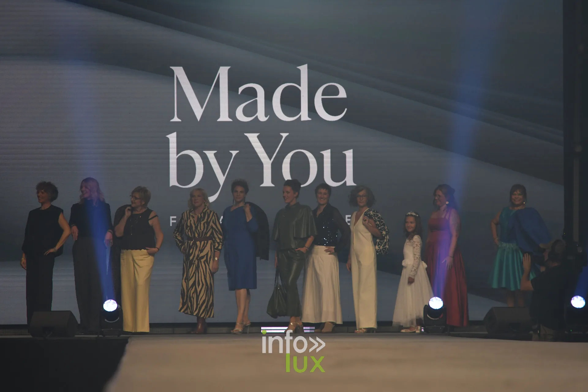 Les participantes de Made by You réunies devant l’écran, dont une enfant en robe blanche — Made by You, école de couture et de stylisme de Charlotte Spoidenne, Lux Fashion Week 2026, Arlon
