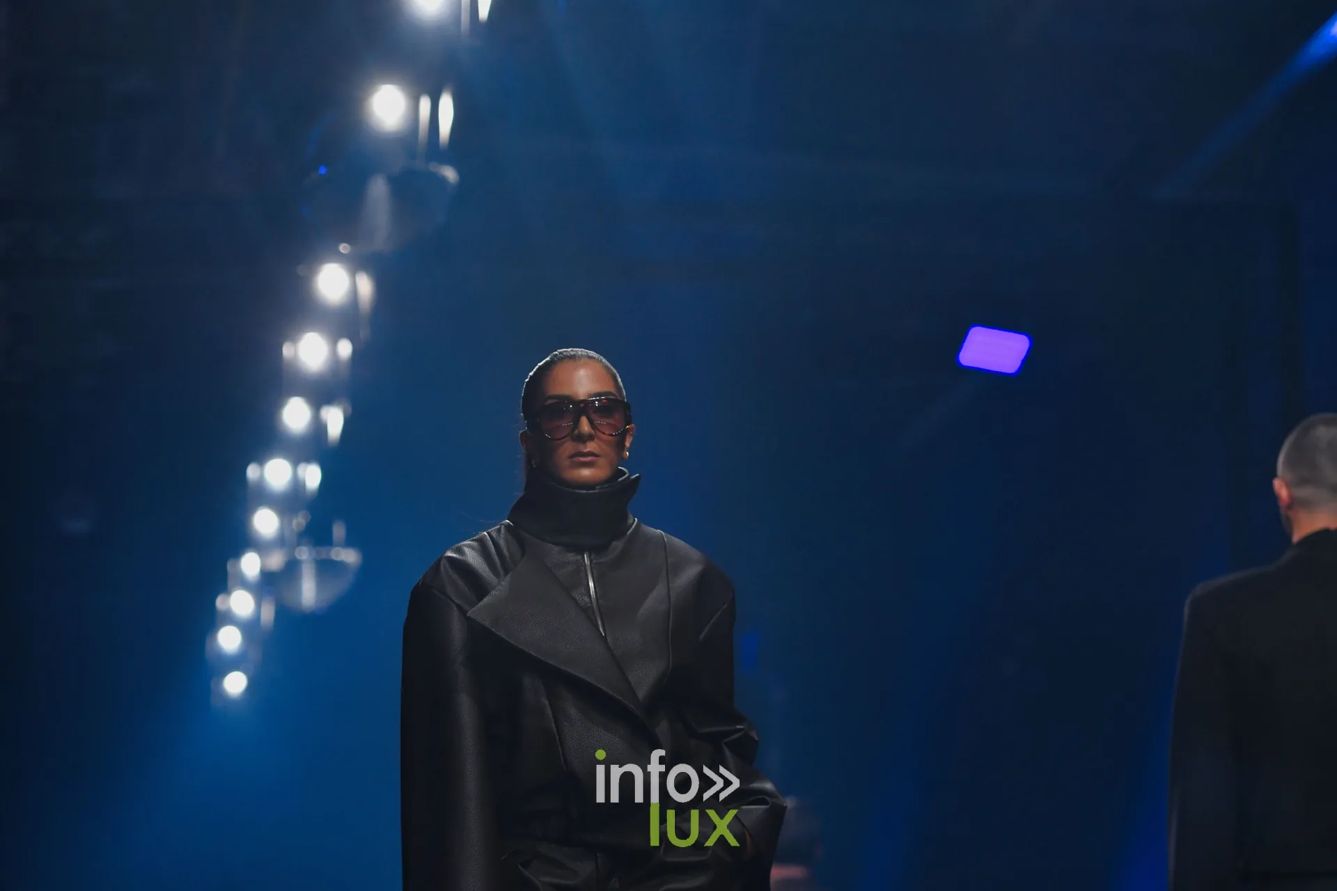 Manteau noir à col montant et lunettes noires, collection « NYRO » de Mathieu Panzokou, Lux Fashion Week 2026, Arlon