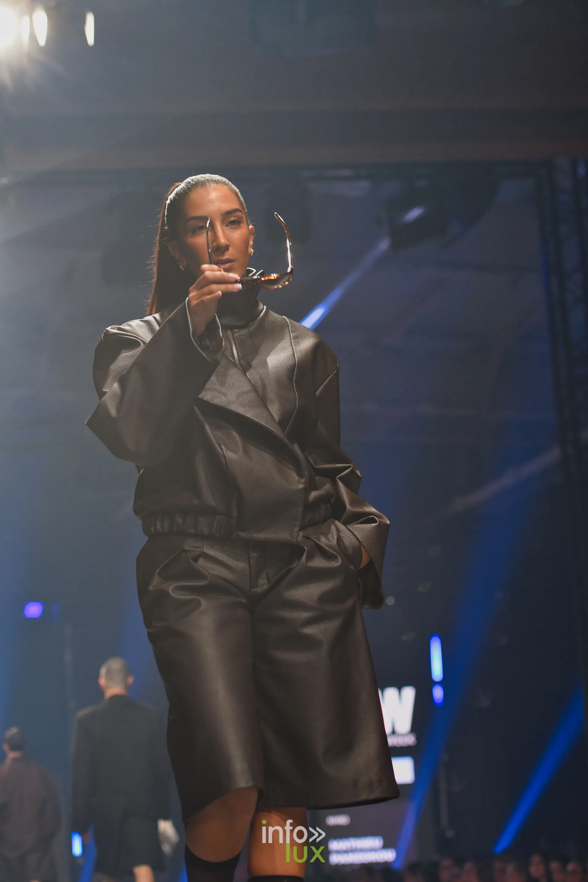 Veste et bermuda en cuir brun, lunettes à la main, collection « NYRO » de Mathieu Panzokou, Lux Fashion Week 2026, Arlon