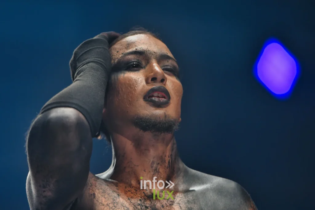 Gros plan d’un mannequin au maquillage craquelé, lèvres sombres, bras recouvert de noir, Lux Fashion Week 2026, Arlon