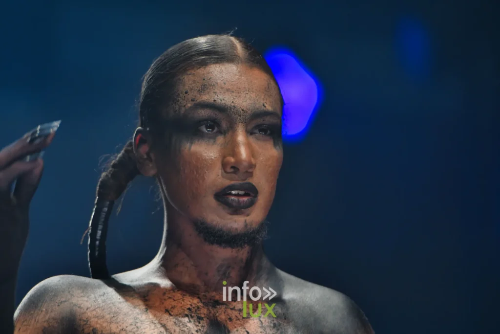 Profil d’un mannequin au maquillage craquelé avec une longue natte, Lux Fashion Week 2026, Arlon