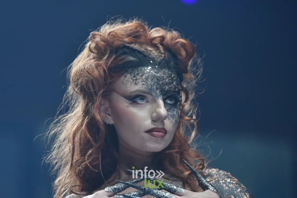 Gros plan d’une mannequin rousse au masque pailleté argent et noir, Lux Fashion Week 2026, Arlon