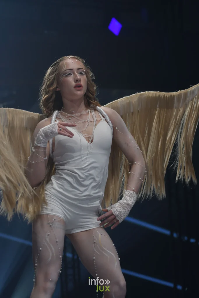 Nova, gants de dentelle blanche et perles, avec ses ailes dorées, Lux Fashion Week 2026, Arlon