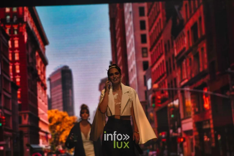 Deux silhouettes devant un décor de rue new-yorkaise projeté à l’écran, dont une cape blanche sur un pantalon noir, collection « Bridal Everyday » de Marie Schweisthal, Lux Fashion Week 2026, Arlon