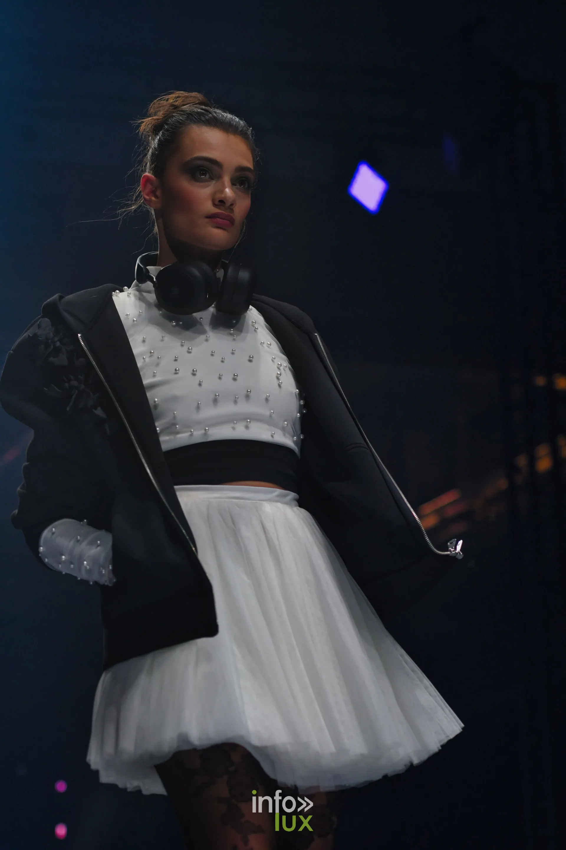 Top blanc perlé, jupe courte en tulle blanc et veste noire zippée, casque audio autour du cou, collection « Bridal Everyday » de Marie Schweisthal, Lux Fashion Week 2026, Arlon