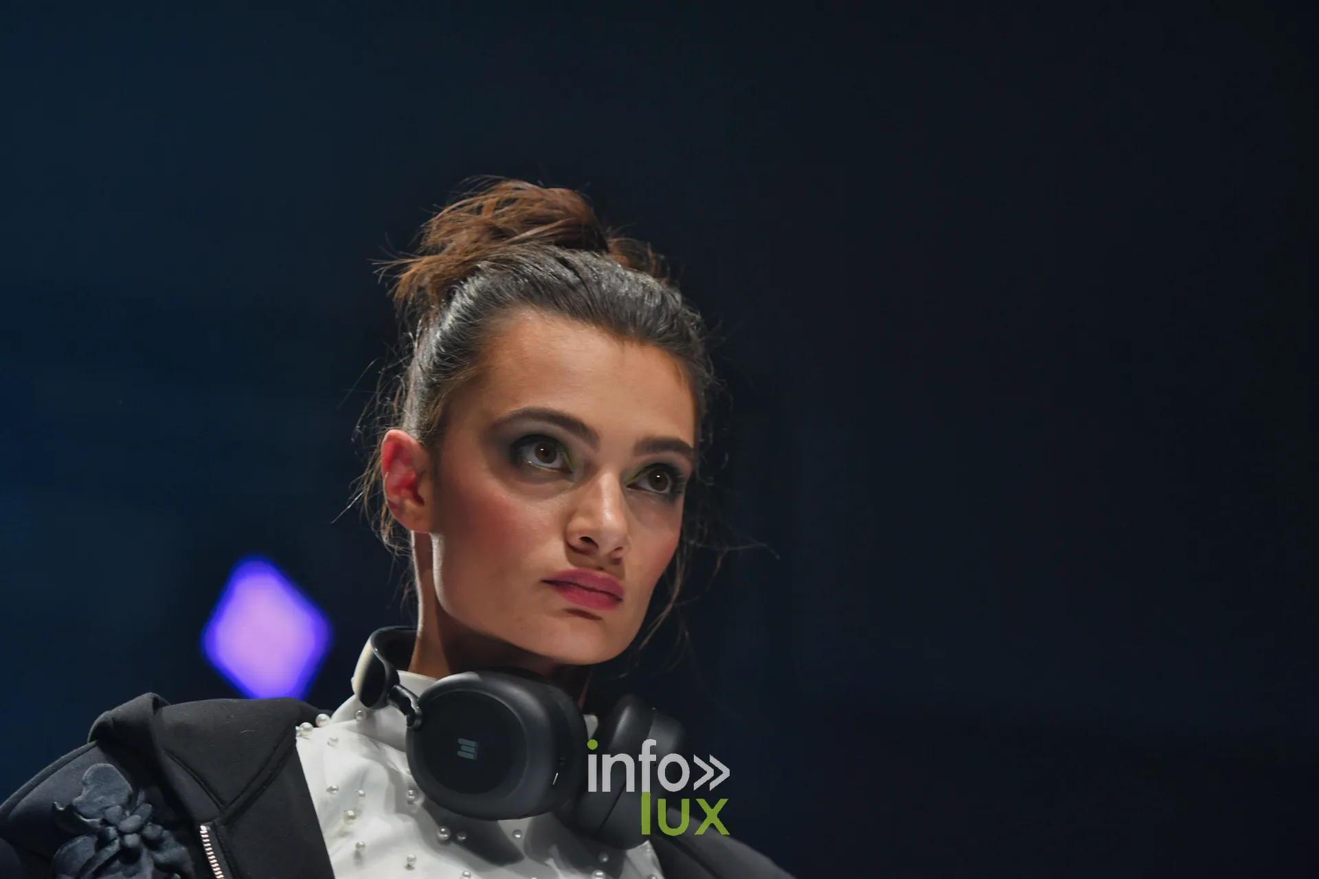 Casque audio noir autour du cou, sur un top blanc perlé et une veste noire, collection « Bridal Everyday » de Marie Schweisthal, Lux Fashion Week 2026, Arlon