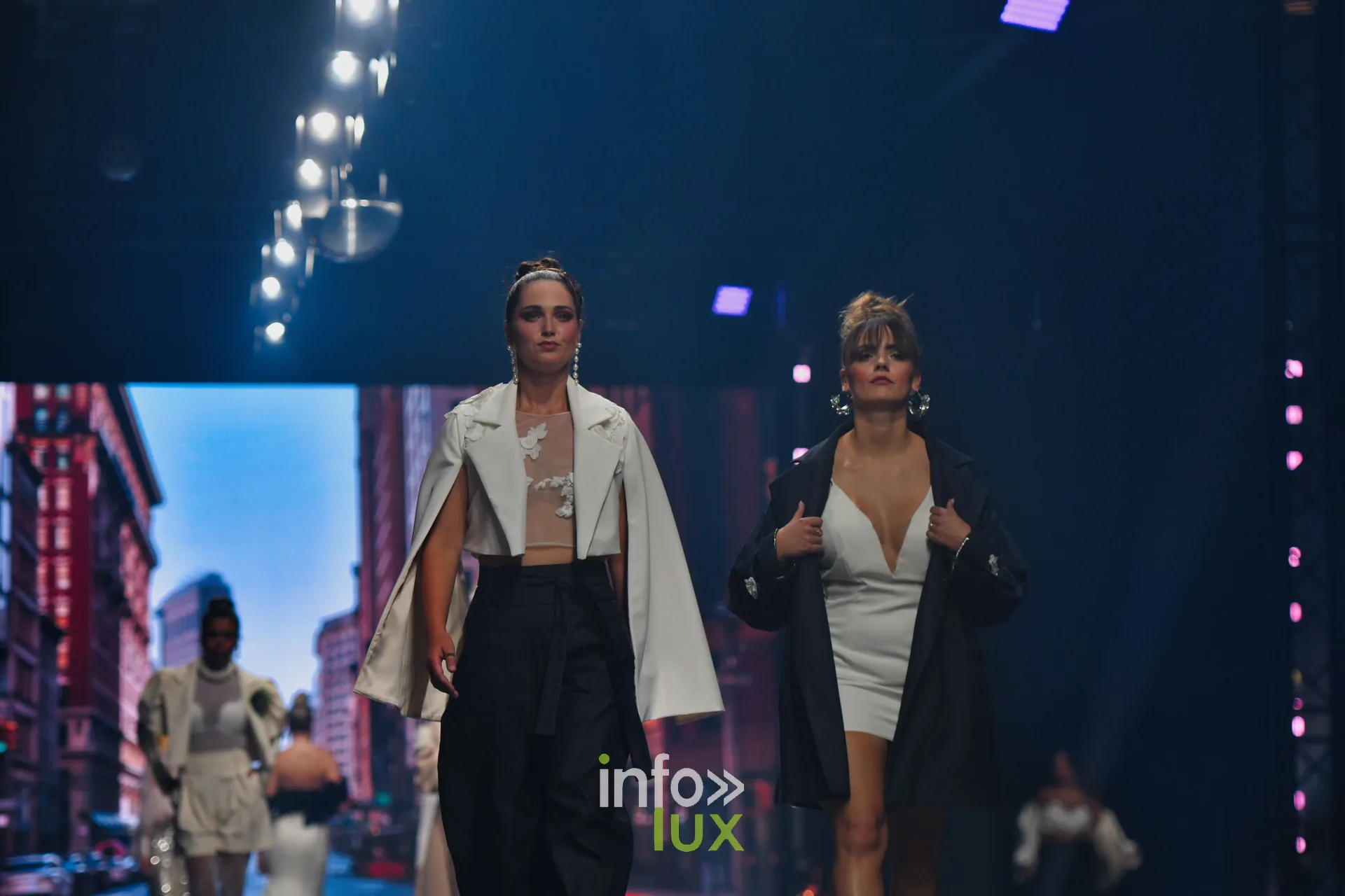 Cape blanche sur pantalon noir et manteau noir sur robe blanche courte, devant le décor new-yorkais, collection « Bridal Everyday » de Marie Schweisthal, Lux Fashion Week 2026, Arlon