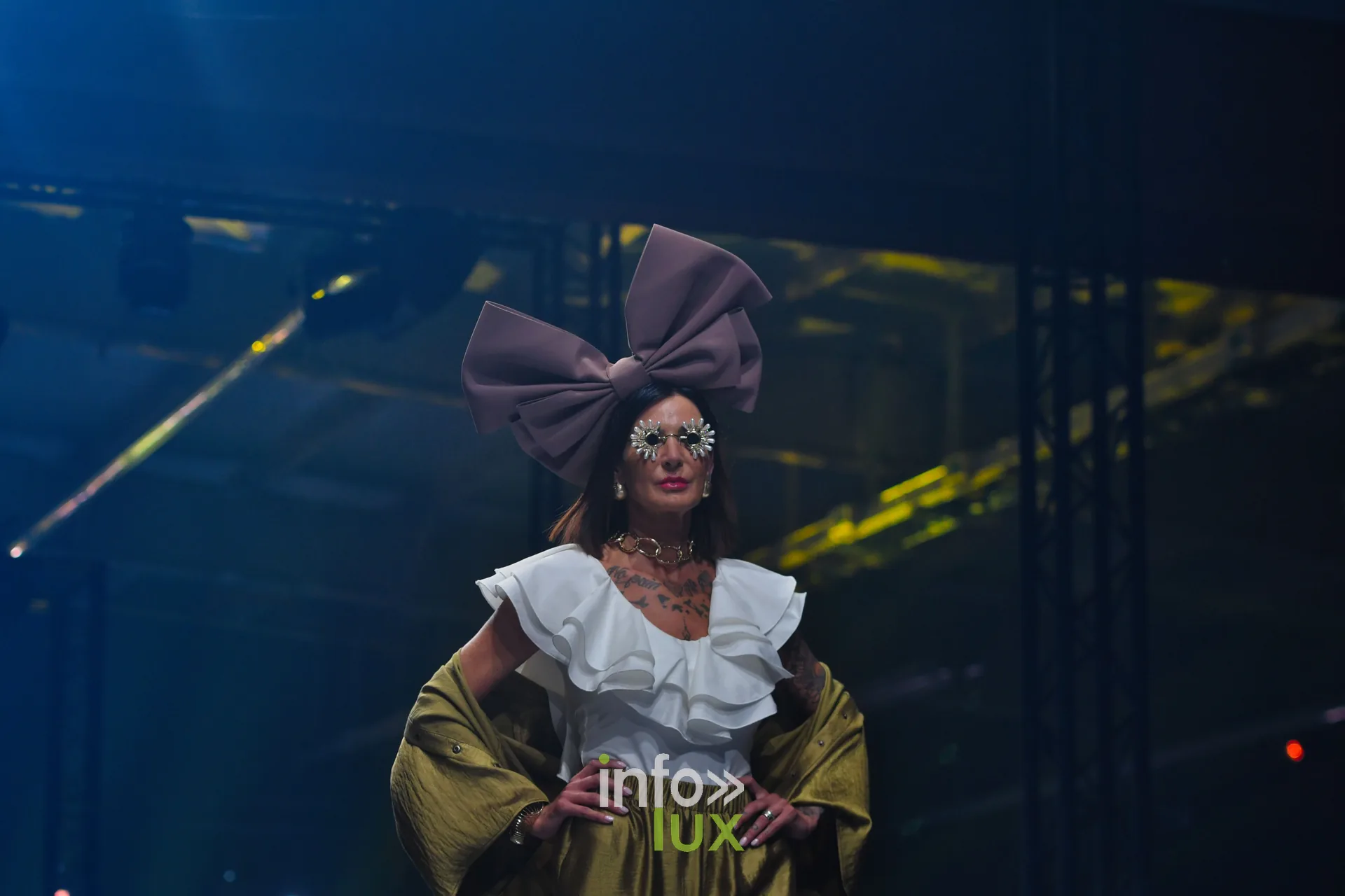 Blouse blanche à volants superposés et pantalon kaki doré, mains sur les hanches — Charlotte Spoidenne, « Diffraction », Lux Fashion Week 2026, Arlon