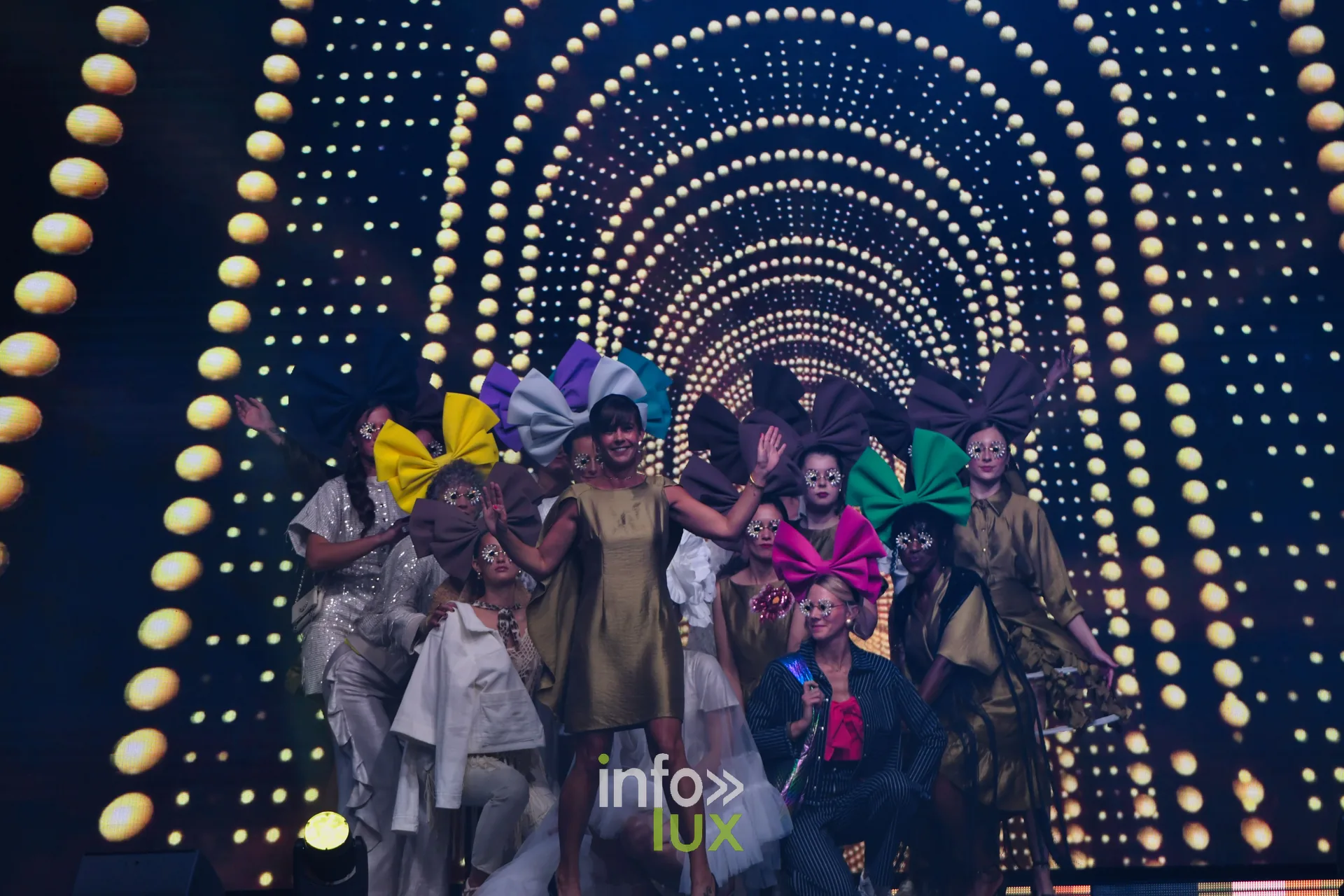 Final sous l’arche lumineuse : les mannequins et leurs nœuds jaune, violet, turquoise, vert et rose — Charlotte Spoidenne, « Diffraction », Lux Fashion Week 2026, Arlon