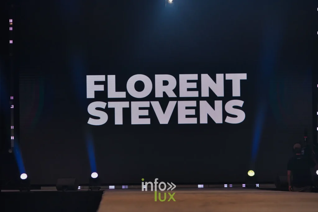 Le nom FLORENT STEVENS affiché sur l’écran de scène avant le passage — Florent Stevens, « S’print », Lux Fashion Week 2026, Arlon