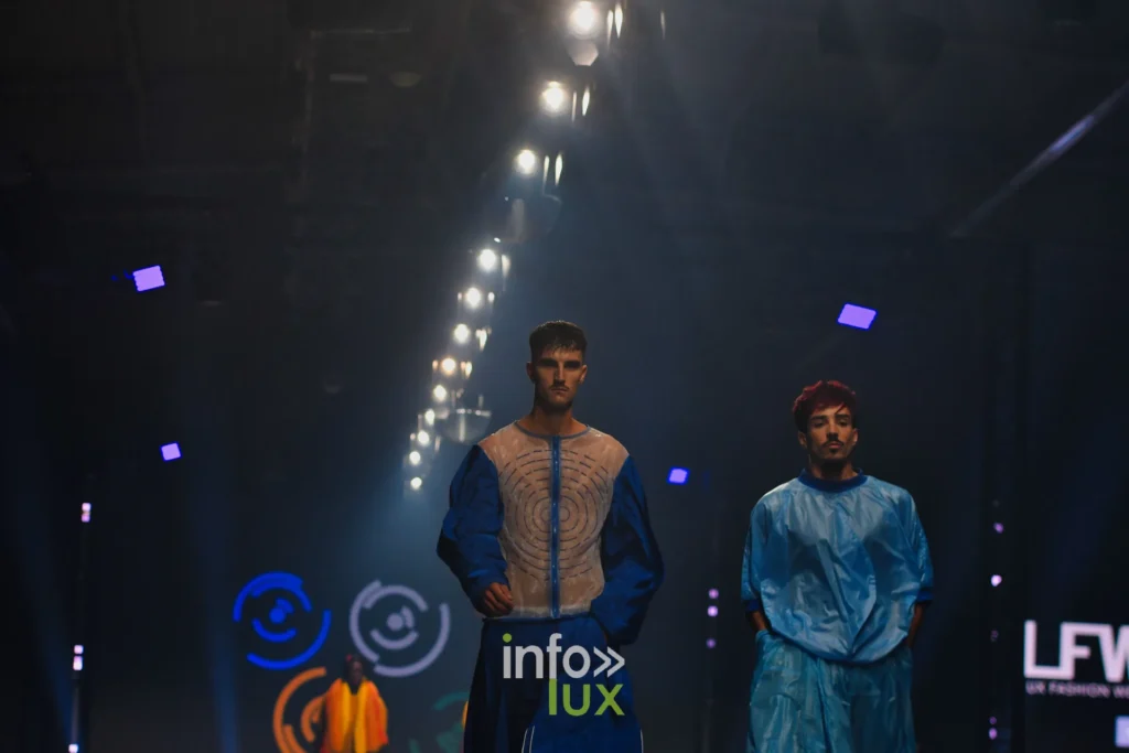 Tunique bleu roi à plastron beige texturé et tunique bleu ciel ample, cercles de couleur à l’écran — Florent Stevens, « S’print », Lux Fashion Week 2026, Arlon