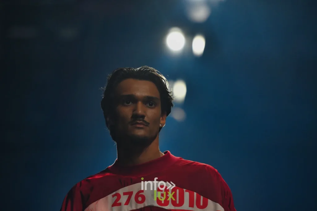 Haut rouge imprimé d’un dossard portant les numéros 276 et 3010 — Florent Stevens, « S’print », Lux Fashion Week 2026, Arlon