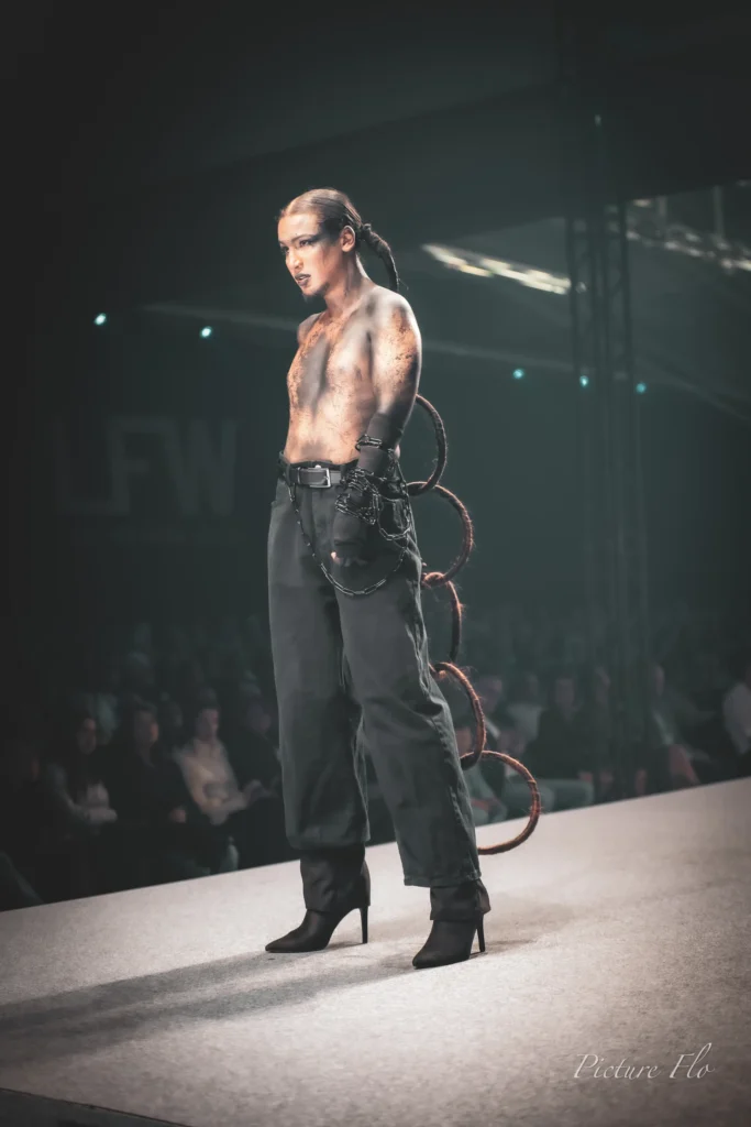 Mannequin torse nu au maquillage craquelé, chaînes et anneaux, sur le podium du show « Les talents de l’ombre », Lux Fashion Week 2026, Arlon