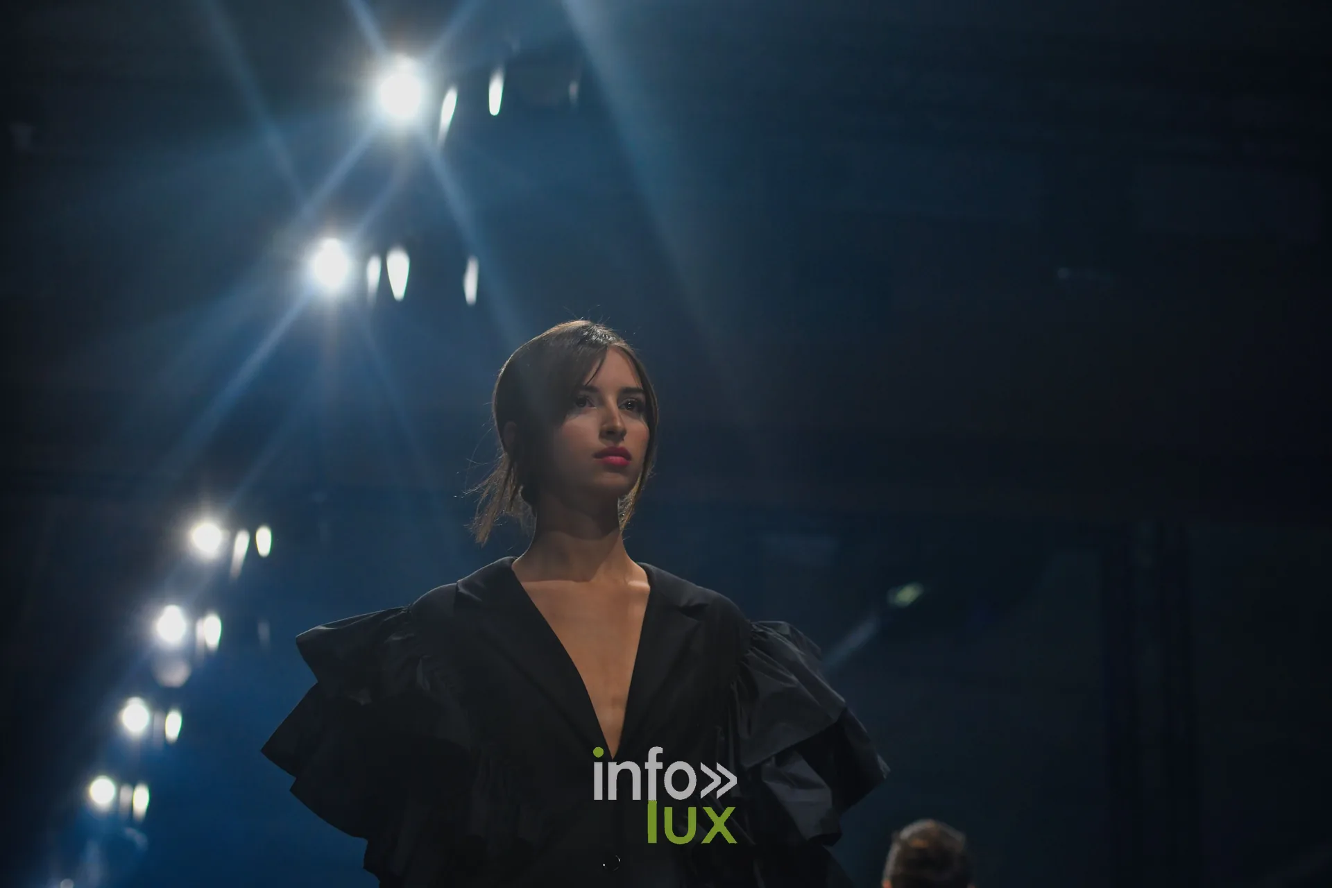 Veste noire à col en V et volants aux épaules — Victoire Waxweiler, « Fragments », Lux Fashion Week 2026, Arlon