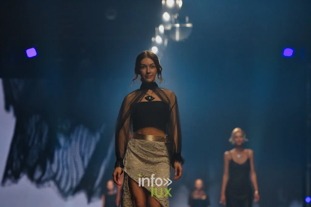 Blouse noire transparente, bandeau noir et jupe portefeuille en dentelle fendue, ceinture dorée — Tania Zorina, « Élégance Florale », Lux Fashion Week 2026, Arlon