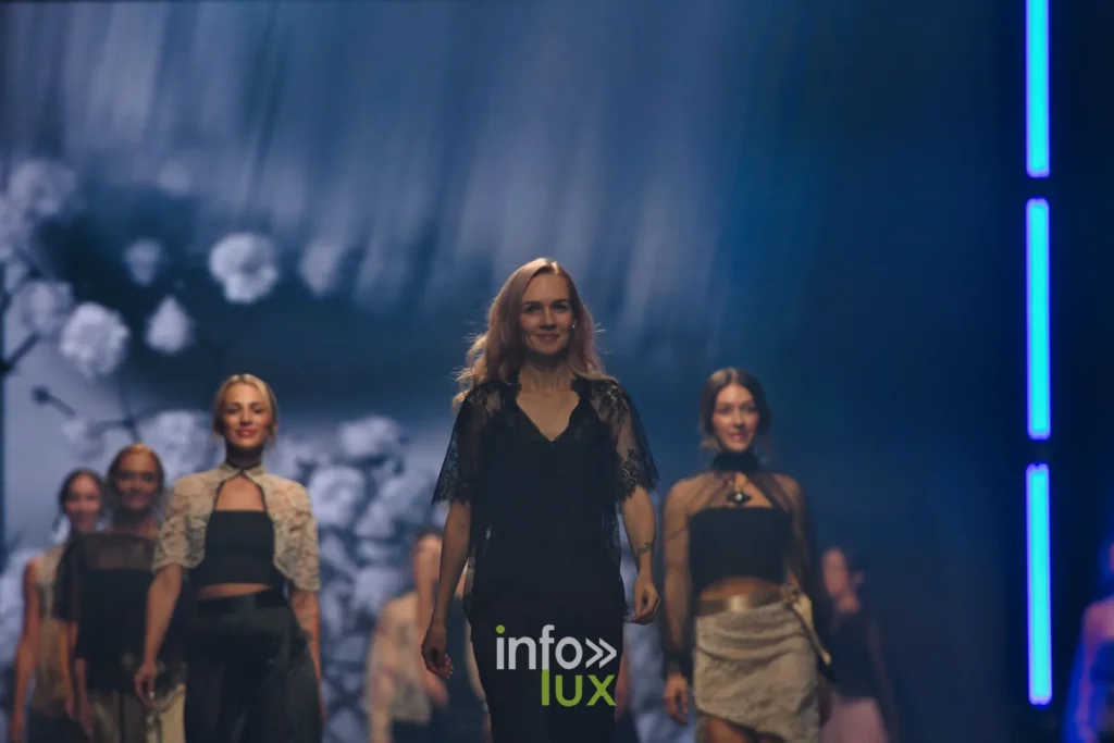 Le groupe au bout du podium, devant l’écran aux fleurs blanches — Tania Zorina, « Élégance Florale », Lux Fashion Week 2026, Arlon