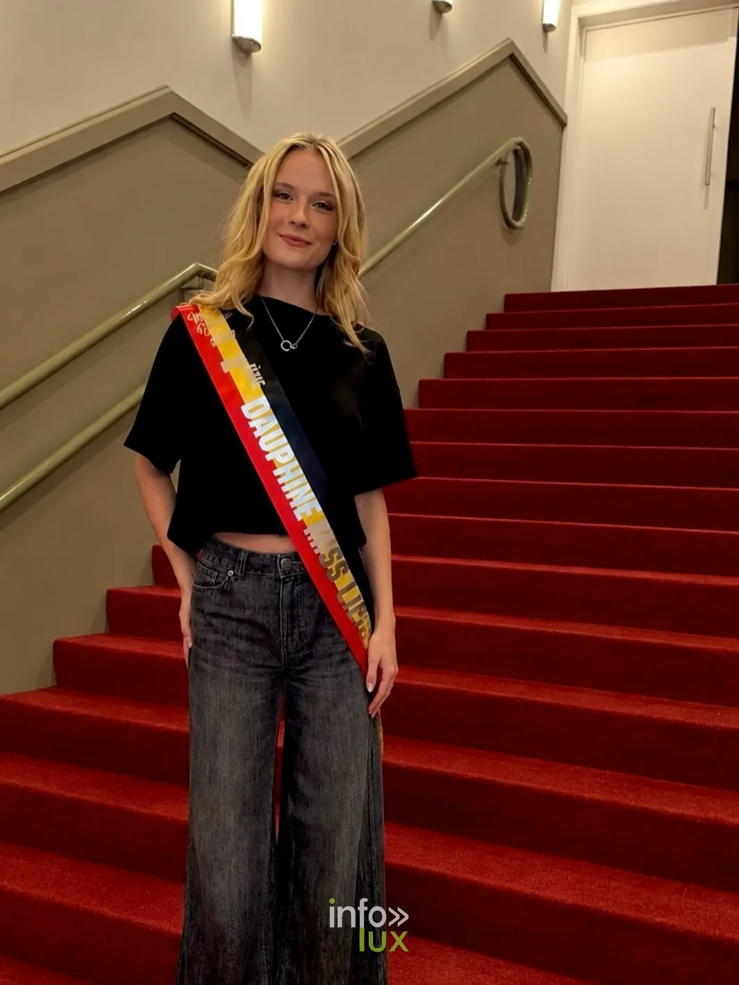 Mackenzie pose avec son écharpe de dauphine dans un escalier au tapis rouge