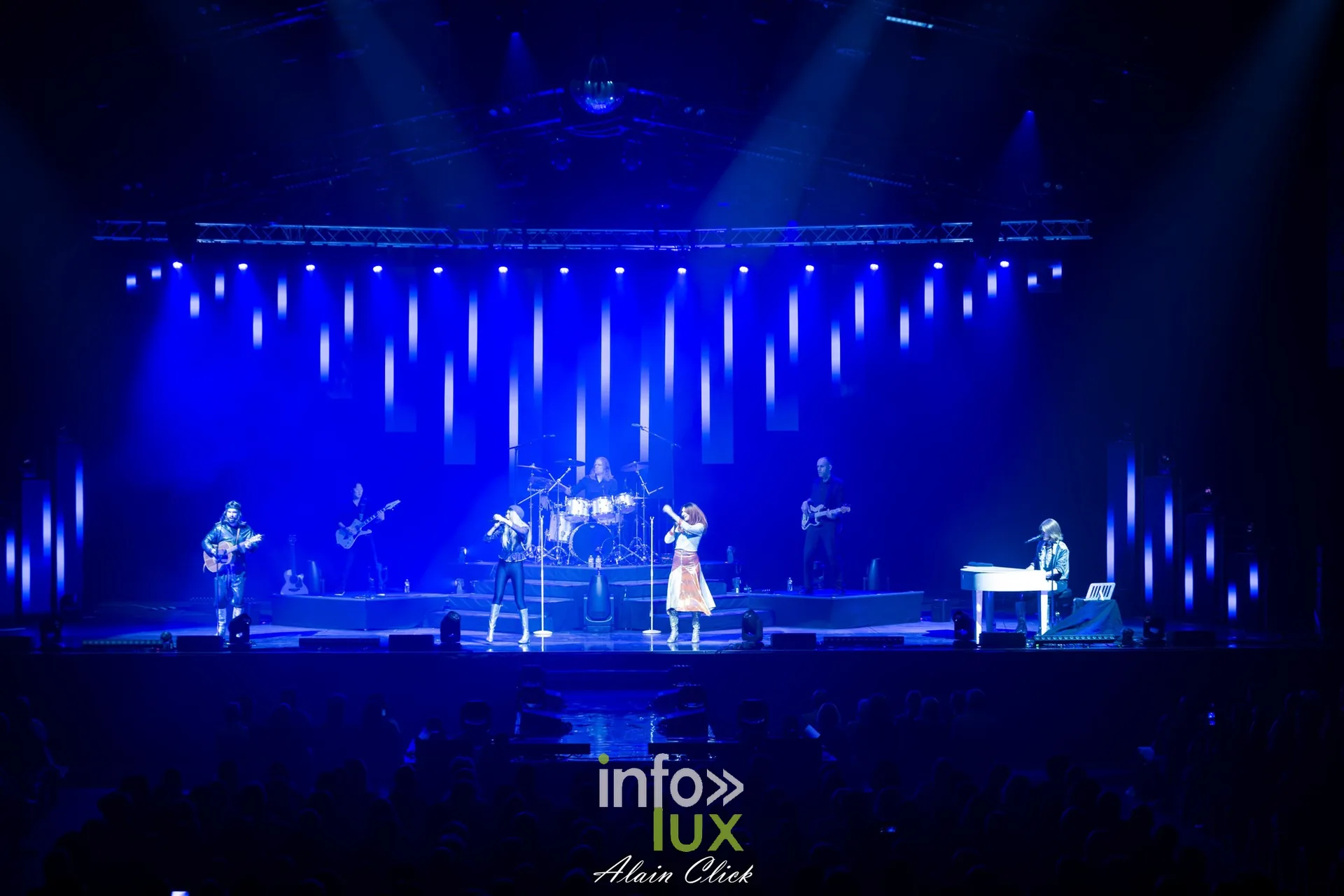 Vue d’ensemble de la scène : le groupe au complet devant un mur de lumières bleues, Mania The ABBA Tribute, Zénith de Nancy, 25 septembre 2026