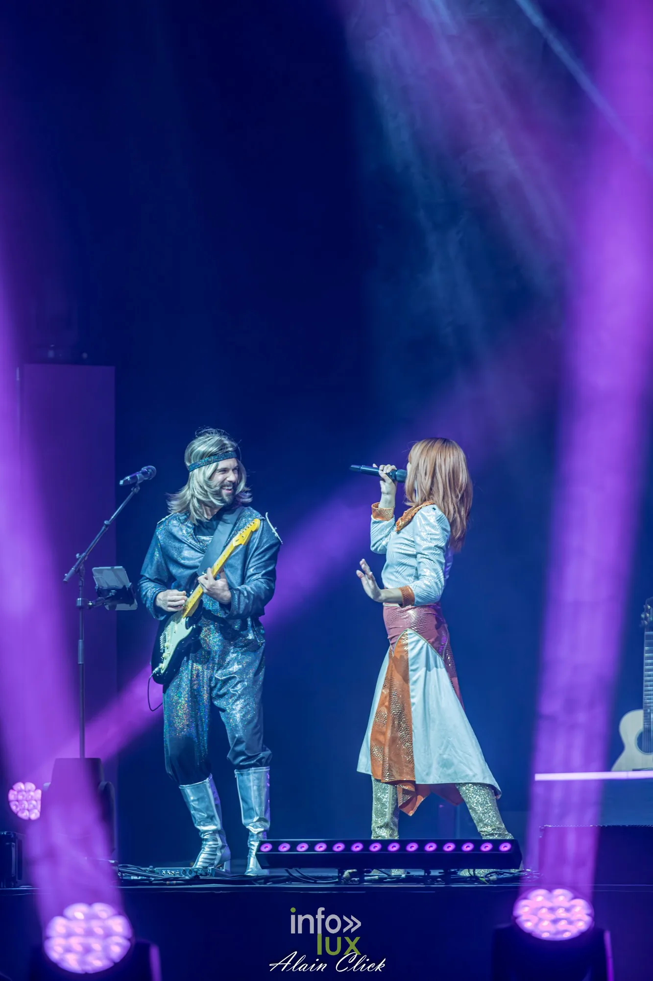 Un guitariste et la chanteuse en jupe cuivrée, faisceaux violets, Mania The ABBA Tribute, Zénith de Nancy, 25 septembre 2026