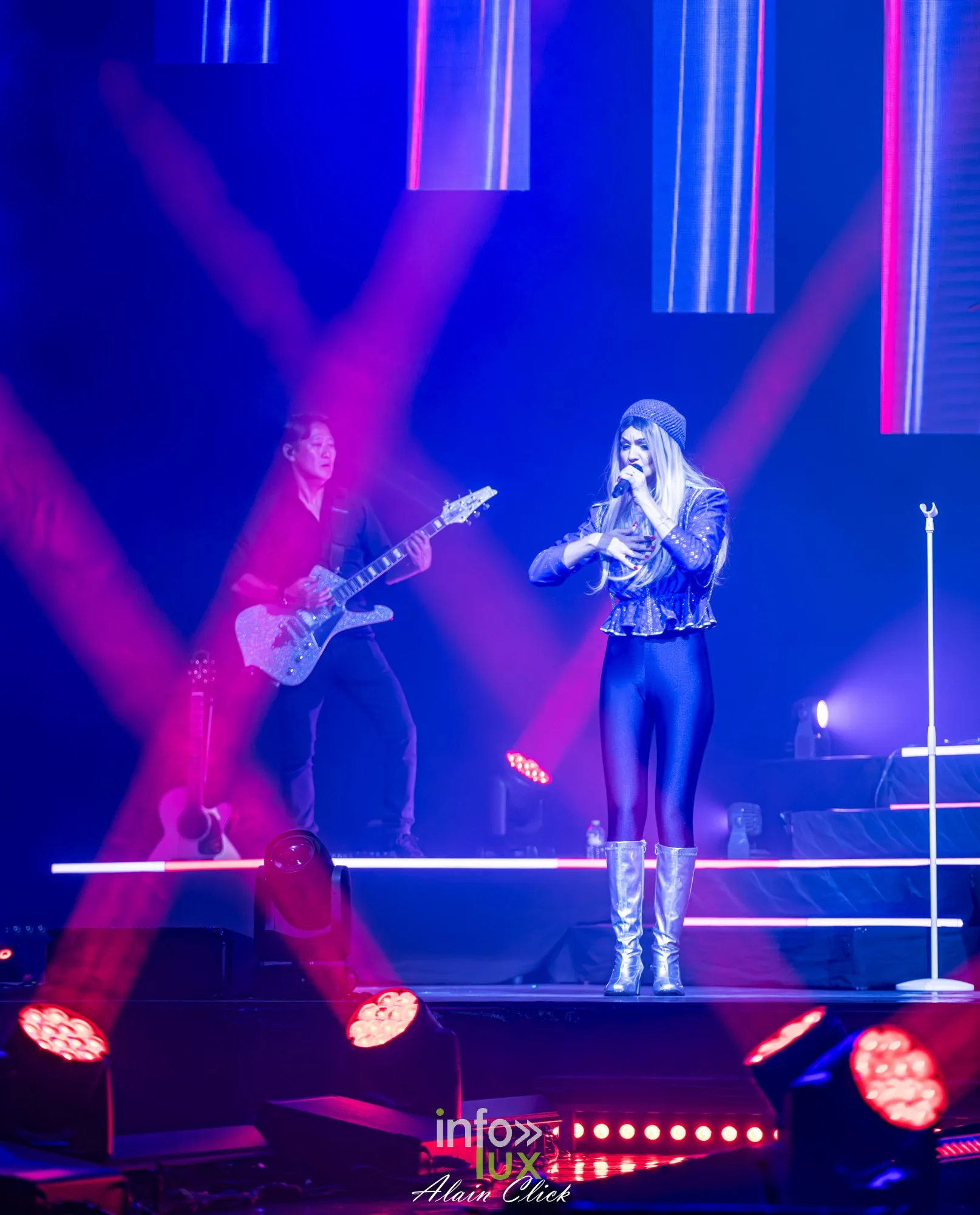 La chanteuse en tenue bleue et un guitariste sous des faisceaux rouges, Mania The ABBA Tribute, Zénith de Nancy, 25 septembre 2026
