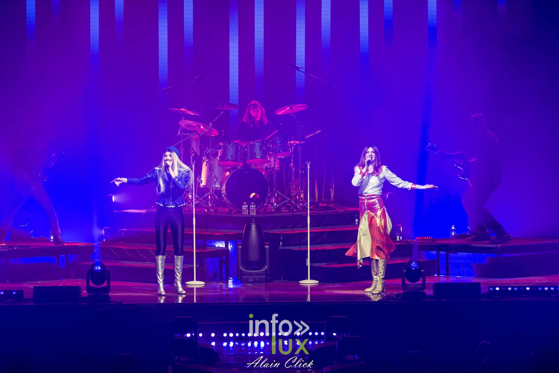Les deux chanteuses au micro, bras tendus, sous une lumière rose et bleue, Mania The ABBA Tribute, Zénith de Nancy, 25 septembre 2026
