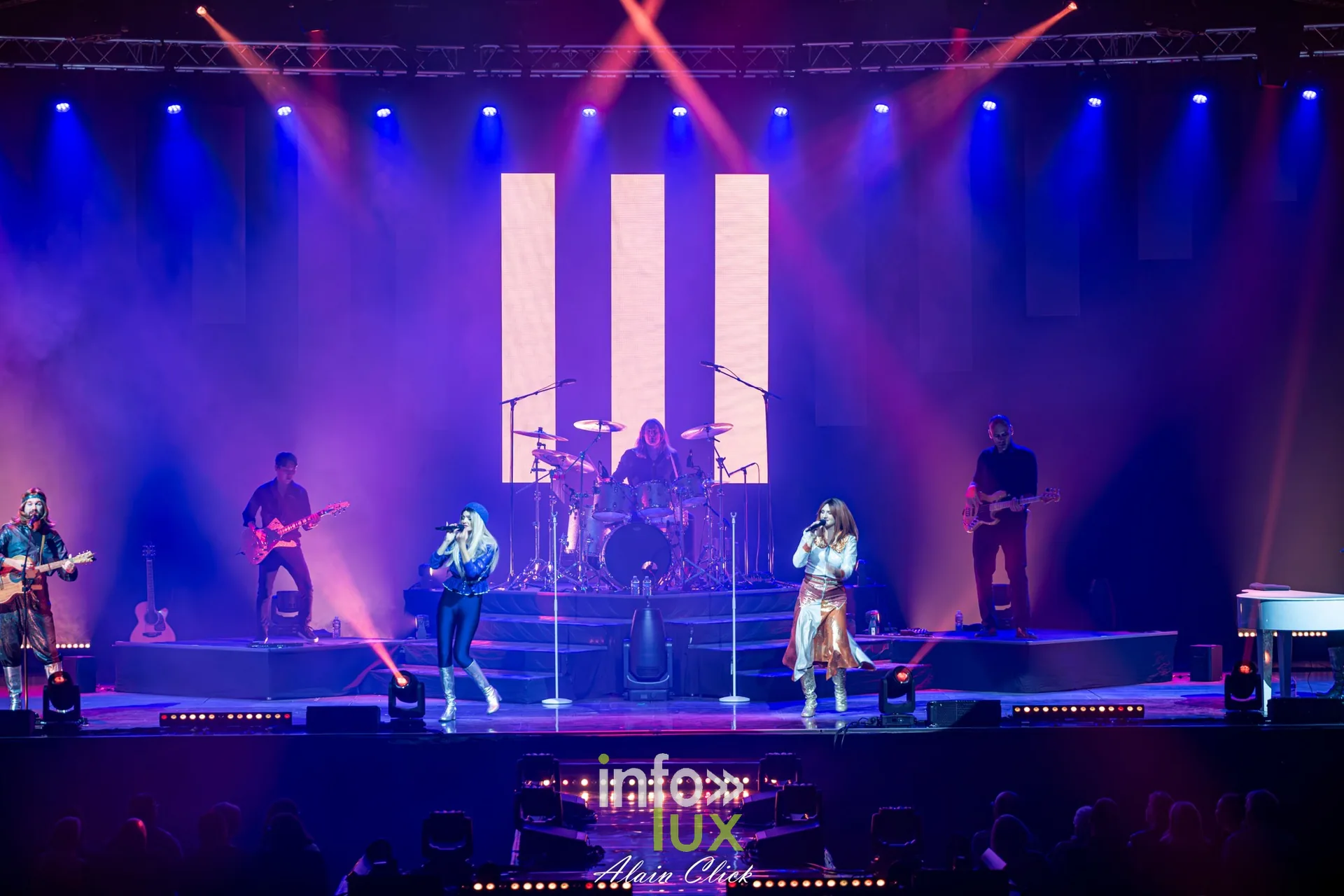 Le groupe au complet devant de grands panneaux lumineux blancs, Mania The ABBA Tribute, Zénith de Nancy, 25 septembre 2026