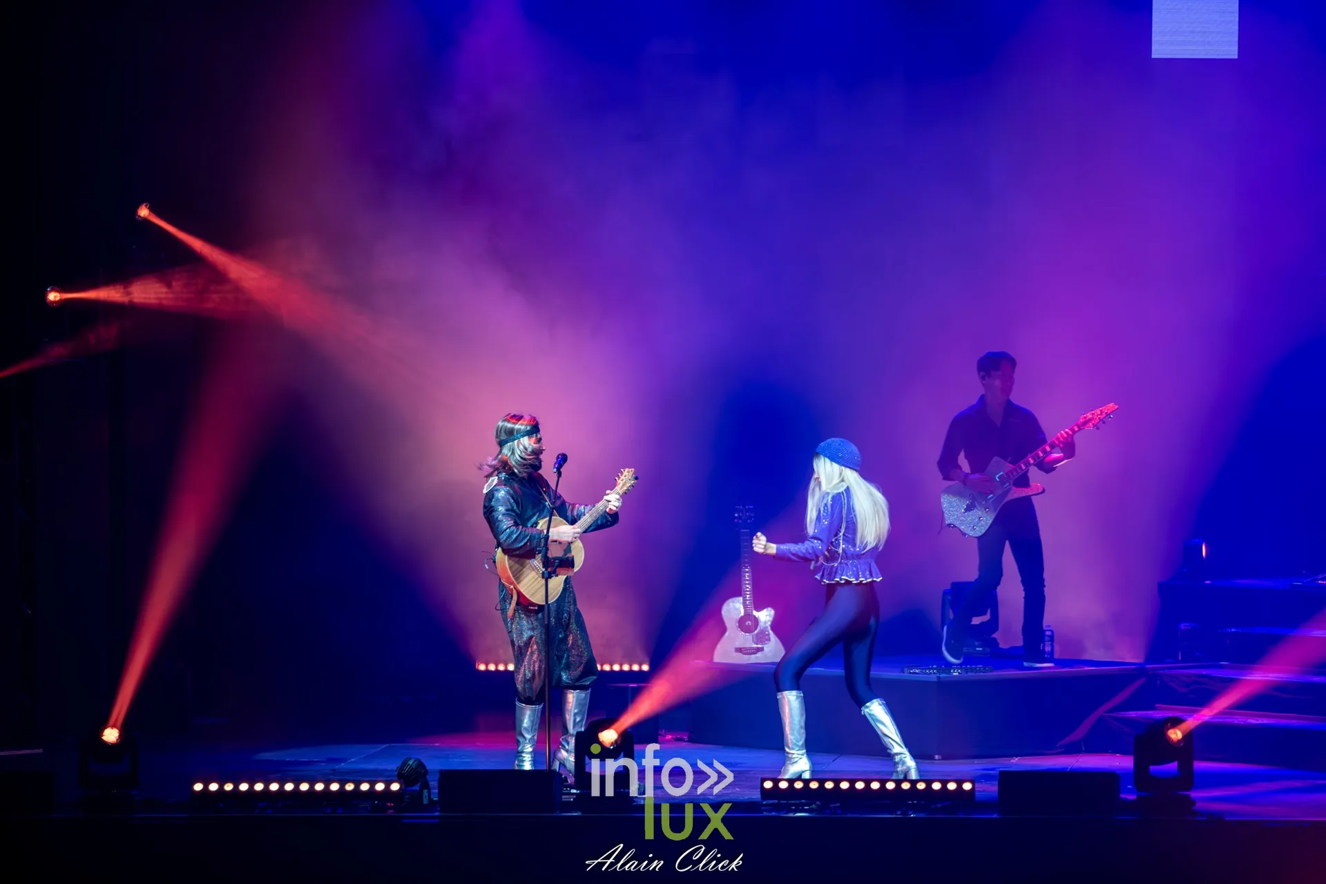 Un guitariste à la guitare acoustique et une chanteuse en tenue bleue, faisceaux rouges, Mania The ABBA Tribute, Zénith de Nancy, 25 septembre 2026