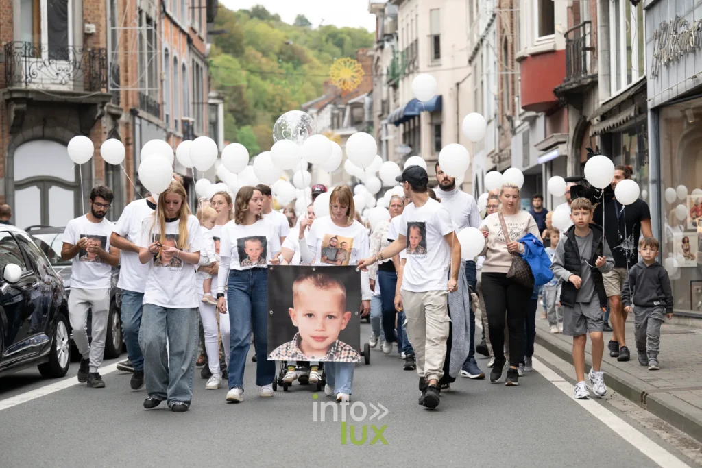 Le cortège de la marche blanche descend la rue Grande à Dinant, derrière le portrait de Tyméo