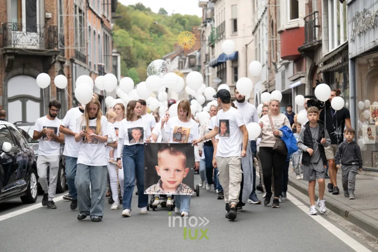 Le cortège de la marche blanche descend la rue Grande à Dinant, derrière le portrait de Tyméo
