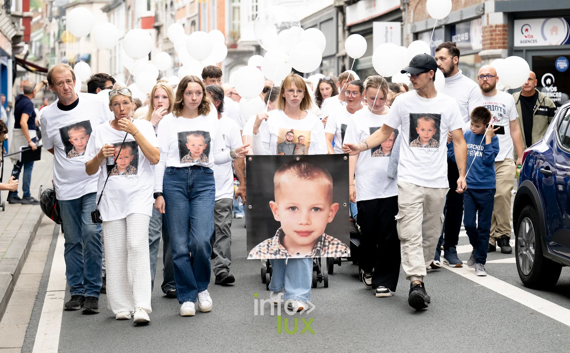Marcheurs en t-shirts blancs et ballons dans une rue de Dinant