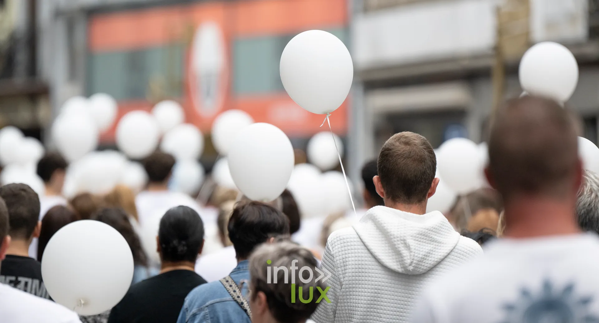 Ballons blancs au premier plan, participants de la marche en arrière-plan