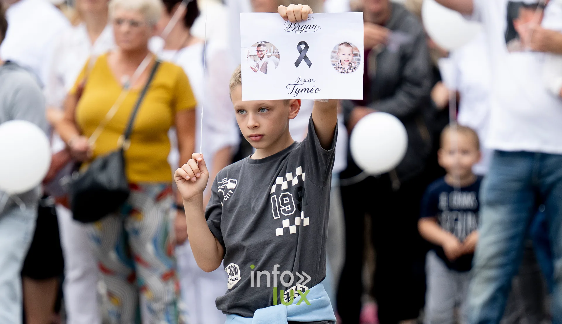 Un enfant brandit une carte d'hommage à Tyméo et Bryan pendant la marche