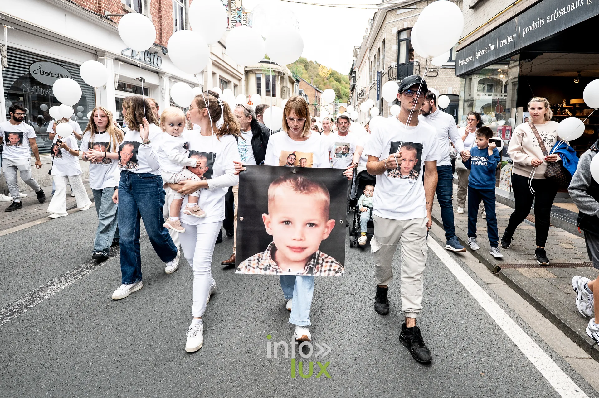 Une femme porte un enfant dans le cortège de la marche blanche à Dinant