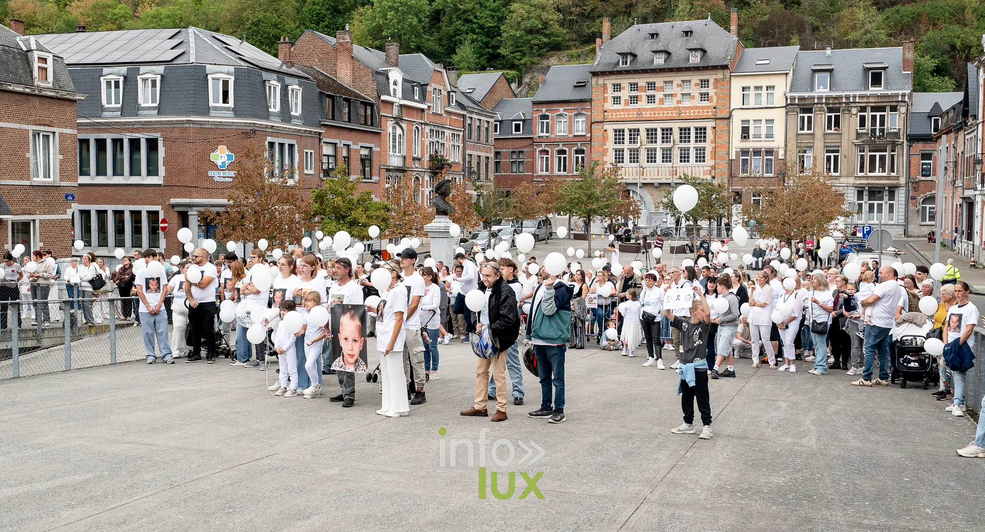Vue large de la foule massée sur l'esplanade au bord de la Meuse à Dinant