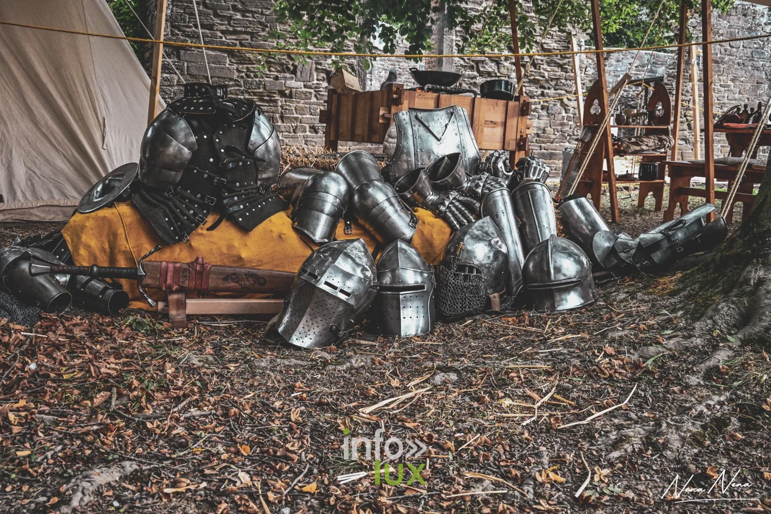 Casques et pièces d’armure posés au sol devant un campement