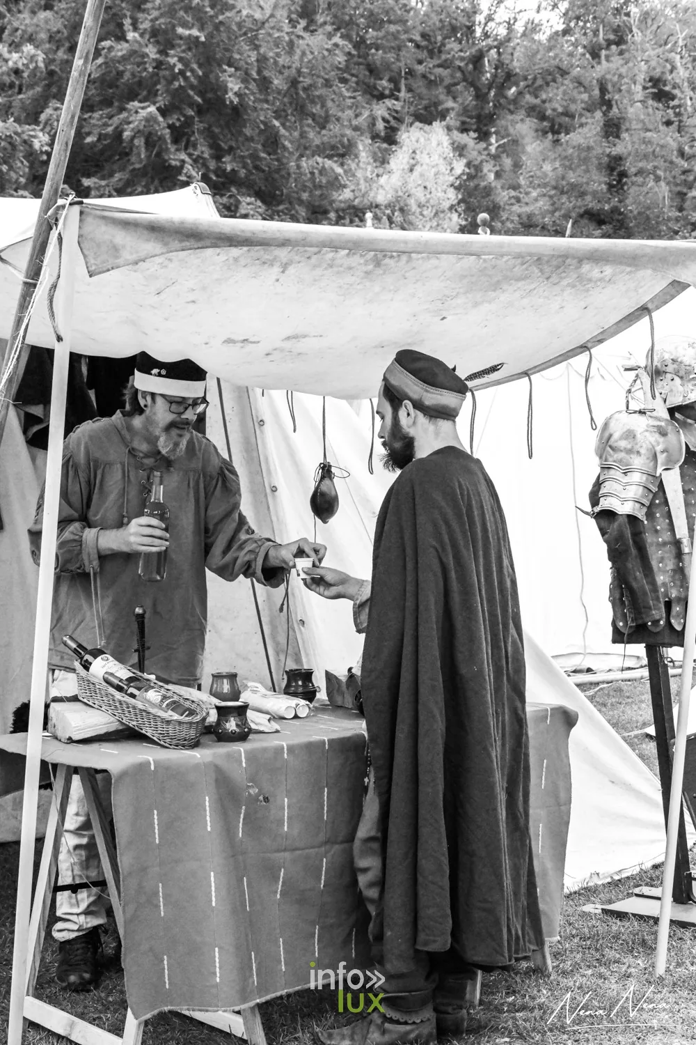 Deux hommes en costume médiéval sous un auvent de toile, en noir et blanc