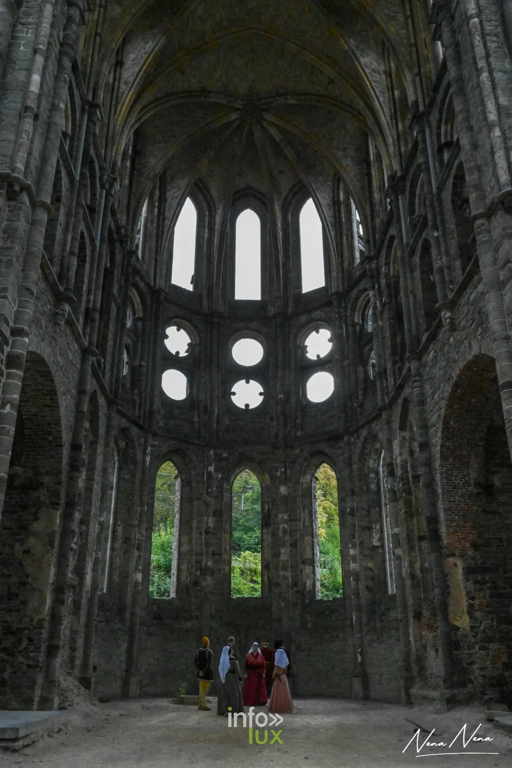 Le chœur en ruine de l’abbatiale de Villers, avec des personnages en costume au fond