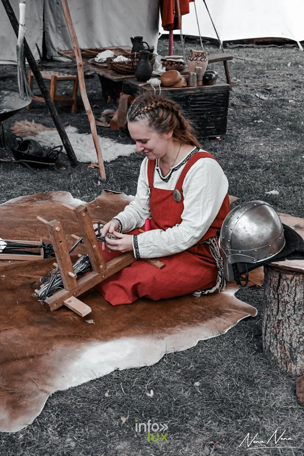 Une jeune femme en robe rouge tisse aux tablettes, un casque posé près d’elle