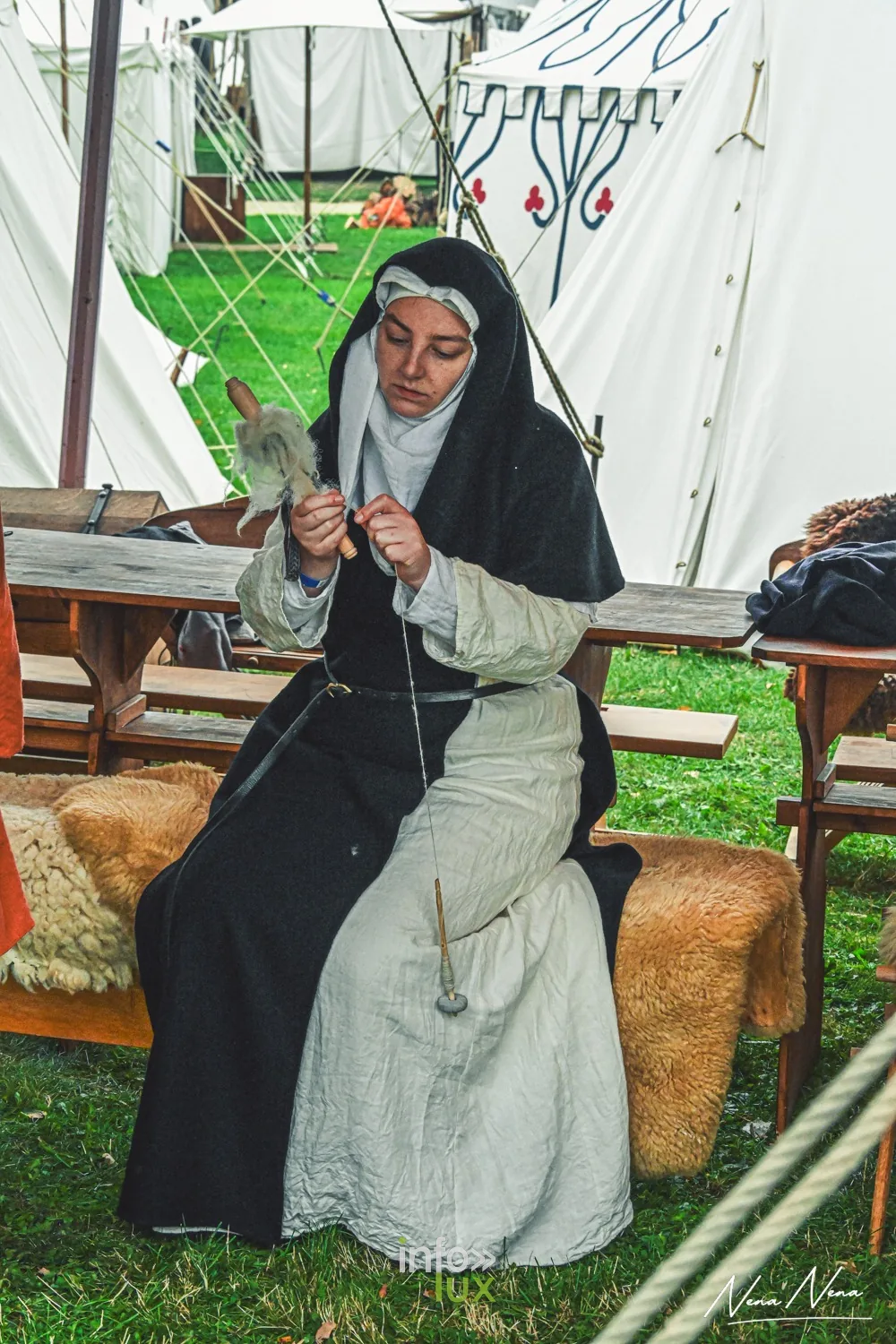 Une femme en habit de religieuse file la laine, assise sur une peau de mouton