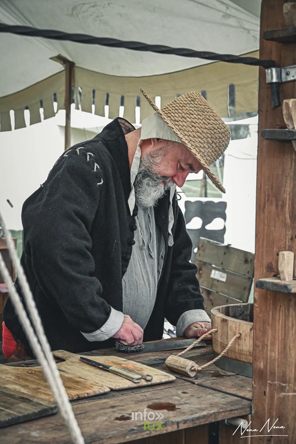 Un artisan âgé au chapeau de paille travaille sur son établi sous une tente