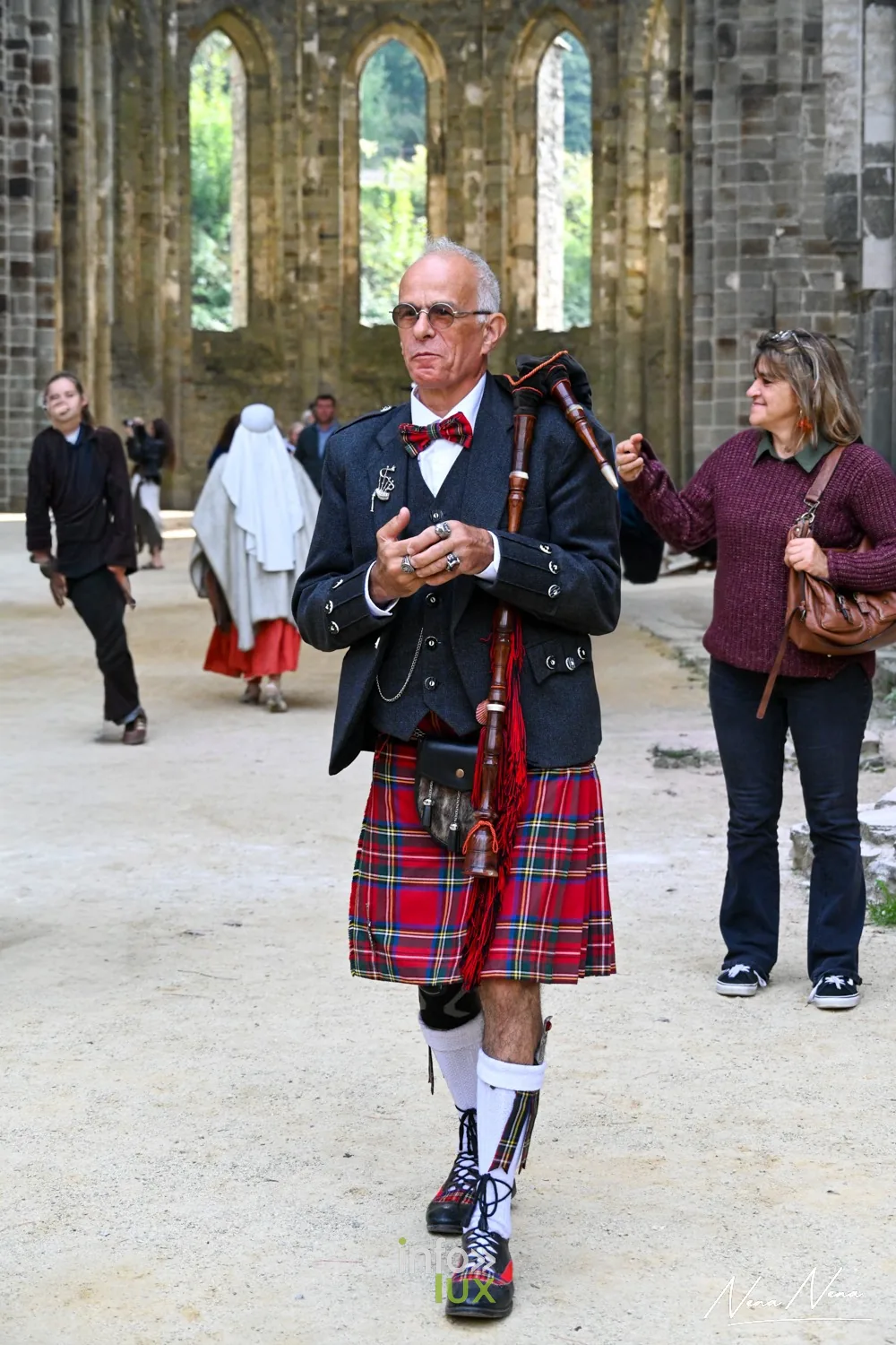 Un homme en kilt écossais et veste joue de la cornemuse dans l’abbatiale en ruine