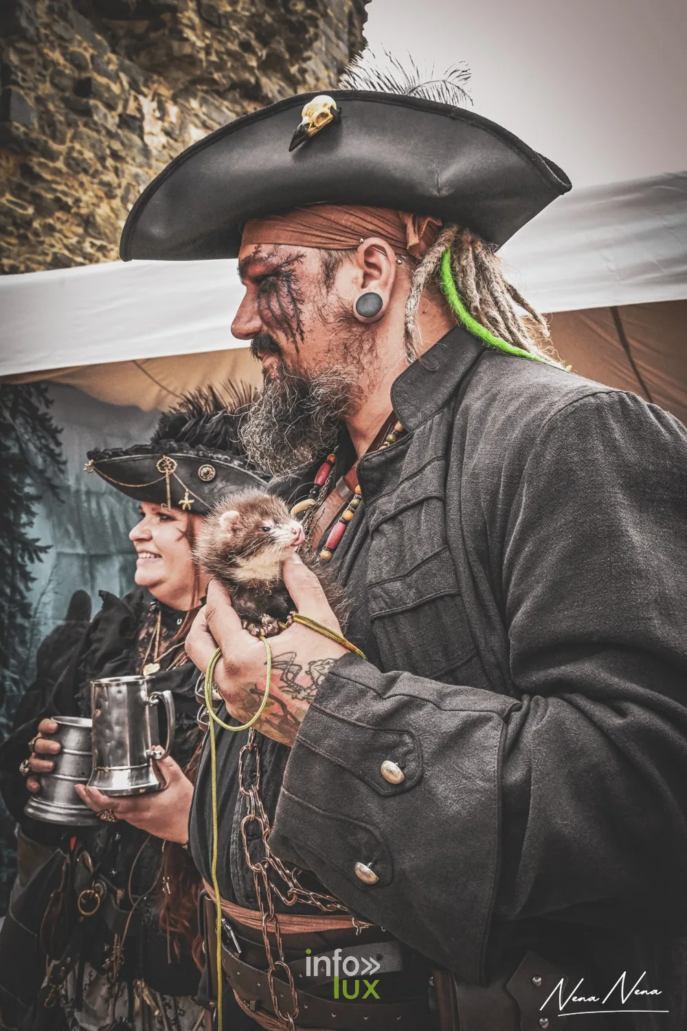 Un couple en costume de pirates, tricorne et furet sur l’épaule, de profil