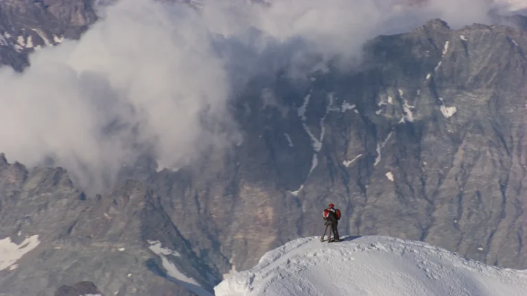 Deux personnes au sommet d'une montagne enneigee en Suisse, image du film Nature pour une reconciliation de Yann Arthus-Bertrand
