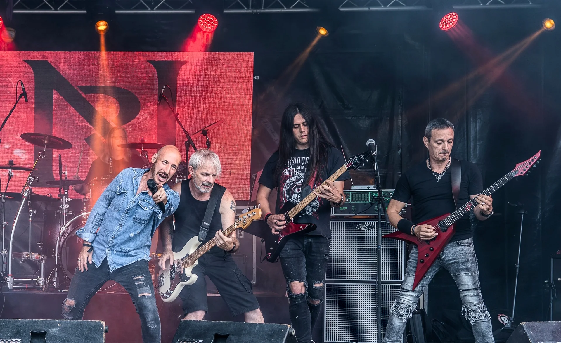 Nightride sur scène en festival, chanteur au micro, bassiste et guitaristes sous les projecteurs