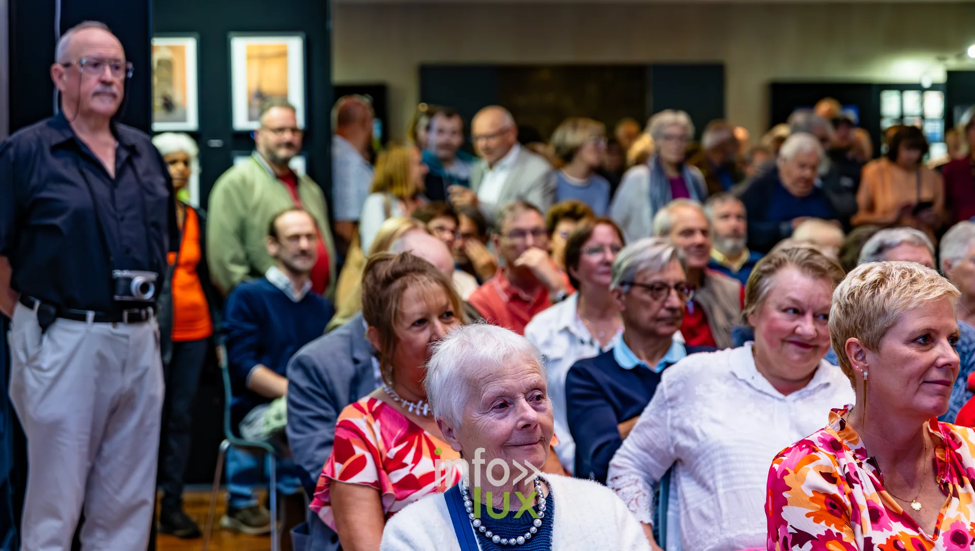 Visiteurs debout au milieu des photographies exposées lors du vernissage du Royal Photo Club Entre Nous à Nivelles