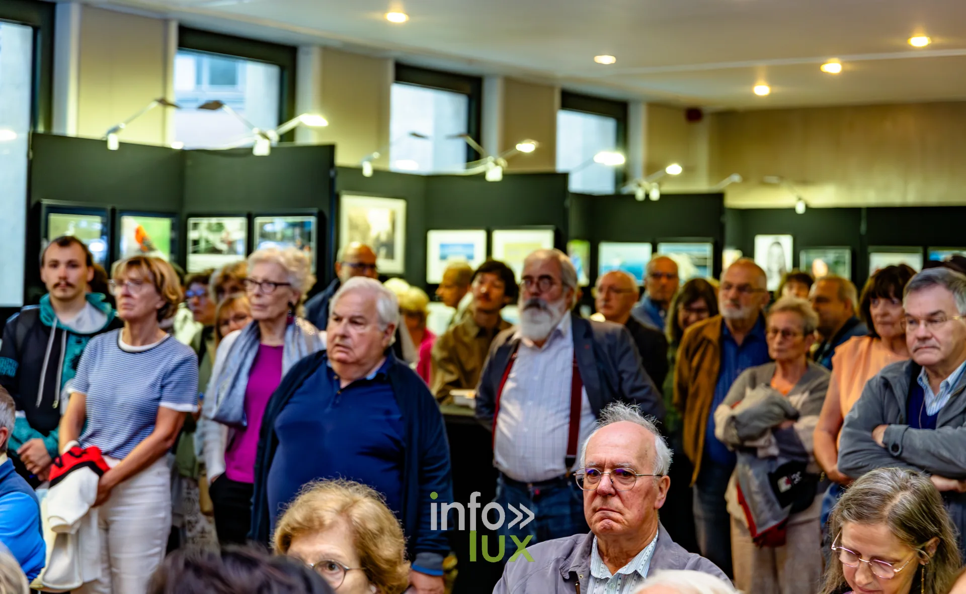 Visiteurs debout au milieu des photographies exposées lors du vernissage du Royal Photo Club Entre Nous à Nivelles