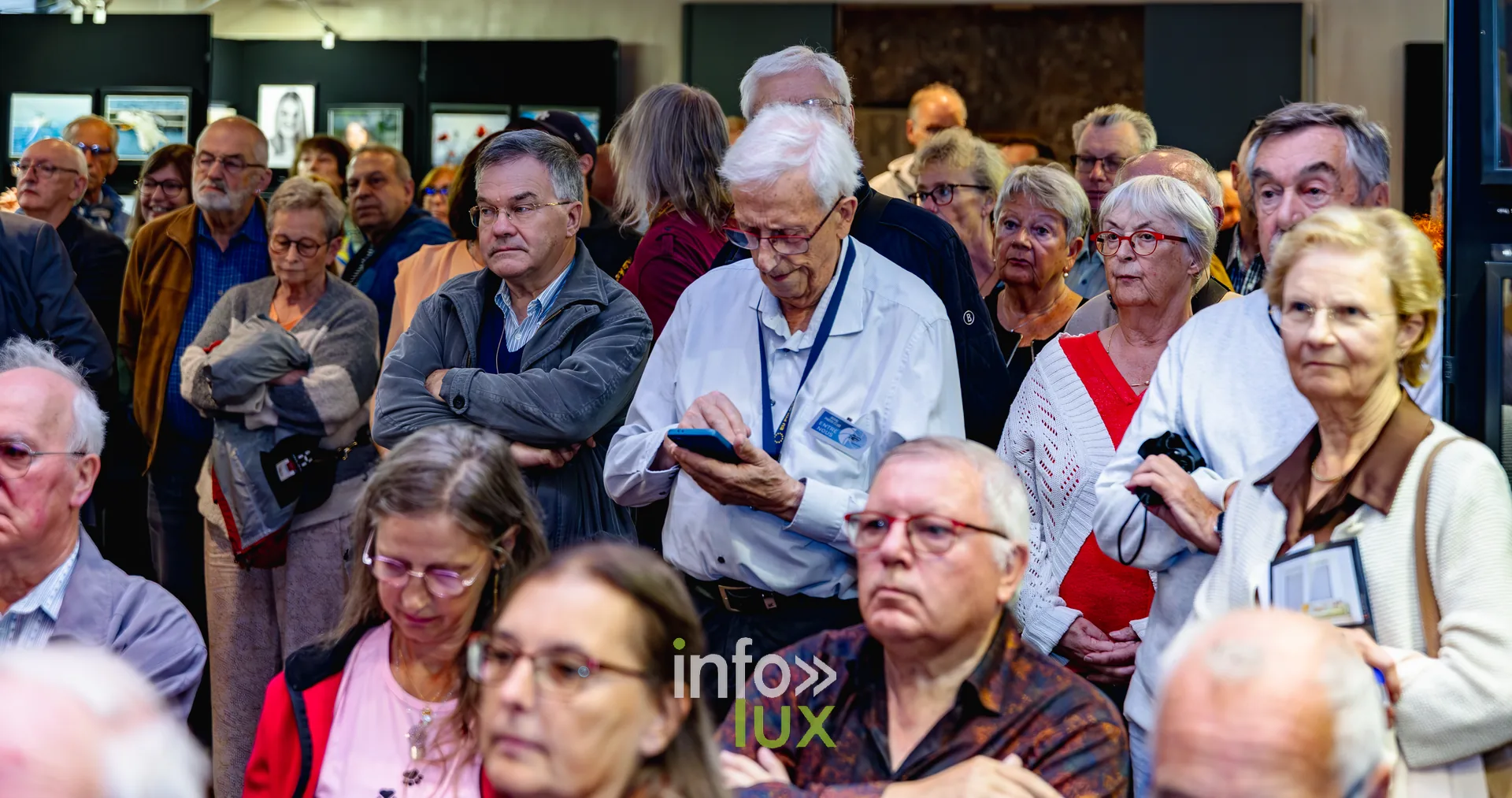 Visiteurs debout au milieu des photographies exposées lors du vernissage du Royal Photo Club Entre Nous à Nivelles