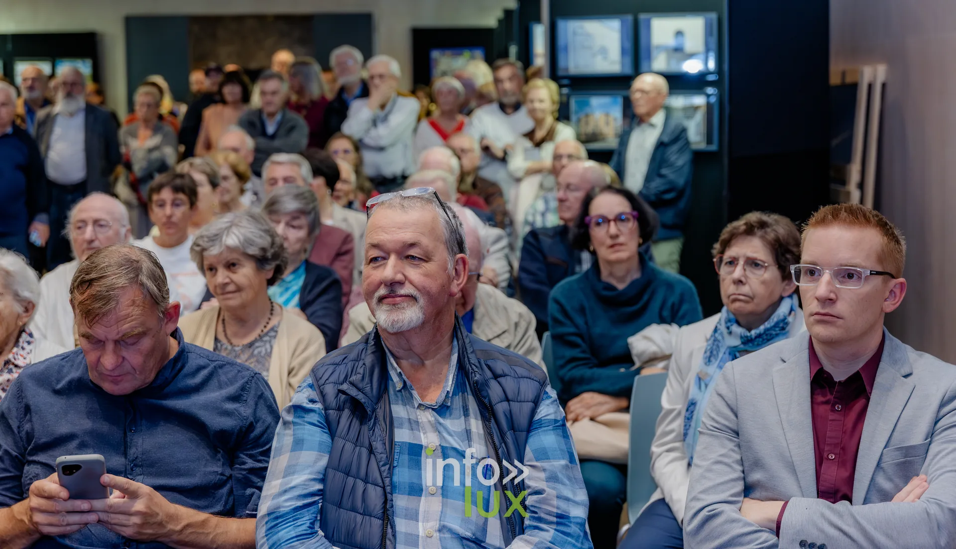Visiteurs debout au milieu des photographies exposées lors du vernissage du Royal Photo Club Entre Nous à Nivelles