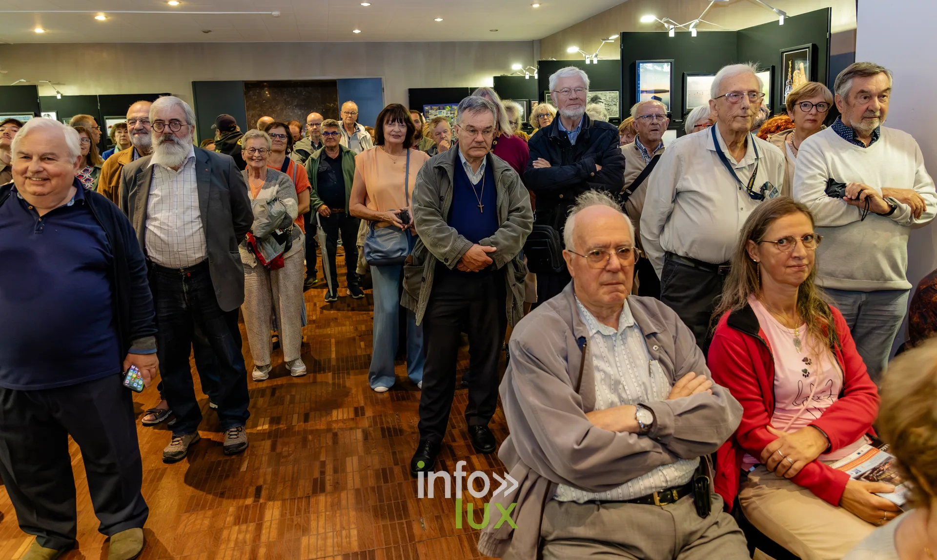 Visiteurs debout au milieu des photographies exposées lors du vernissage du Royal Photo Club Entre Nous à Nivelles